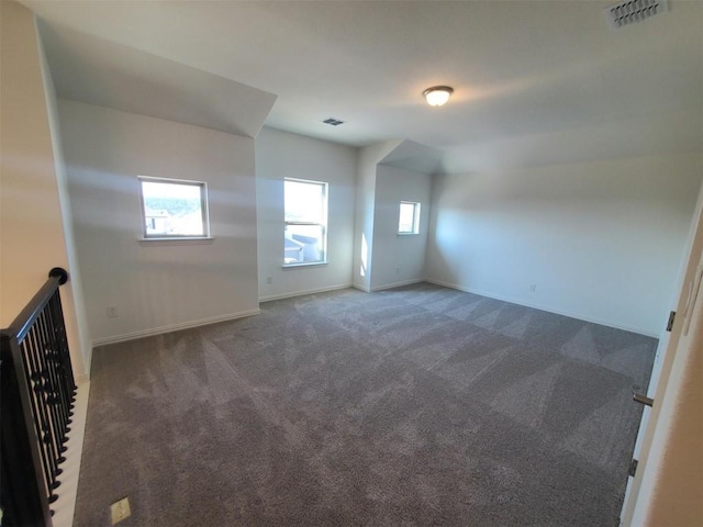 spare room with baseboards, visible vents, and dark colored carpet