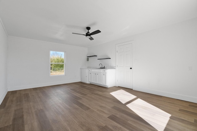 unfurnished living room with sink, hardwood / wood-style flooring, and ceiling fan