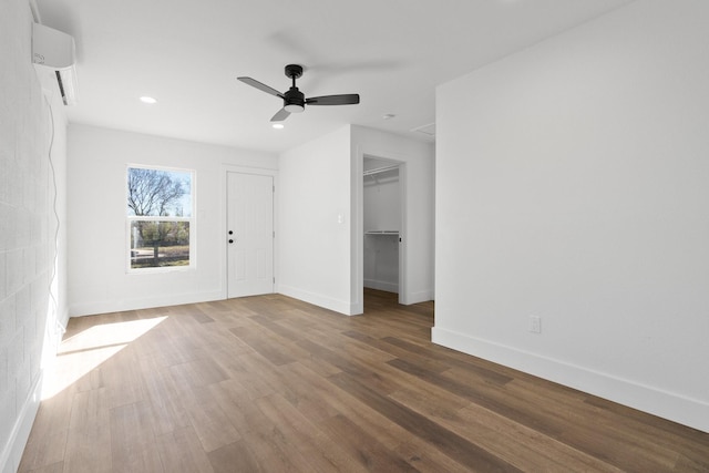 interior space with an AC wall unit, hardwood / wood-style floors, and ceiling fan