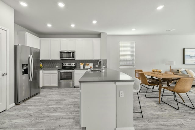 kitchen with sink, appliances with stainless steel finishes, white cabinetry, light hardwood / wood-style floors, and kitchen peninsula