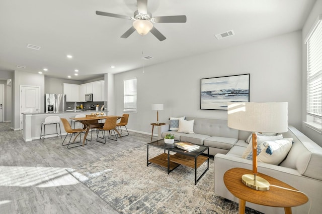 living room featuring light hardwood / wood-style flooring and ceiling fan