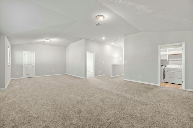 unfurnished living room featuring vaulted ceiling, washer and dryer, and light carpet