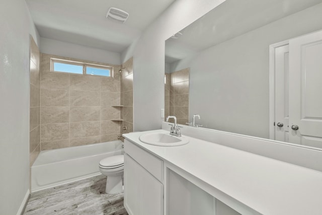 full bathroom with tiled shower / bath, hardwood / wood-style floors, vanity, and toilet