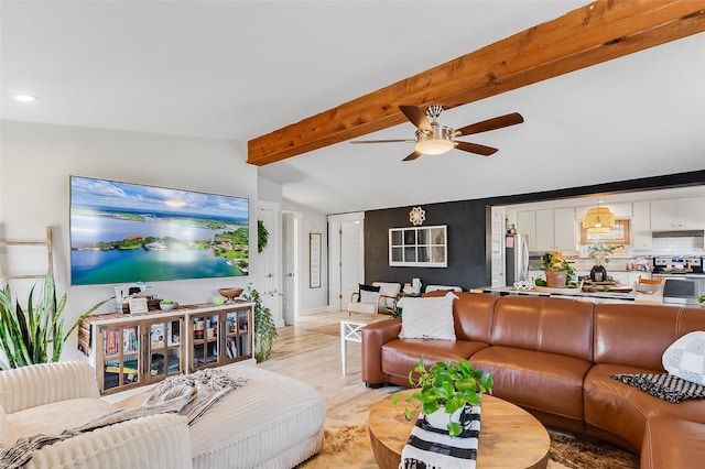 living room featuring ceiling fan, light hardwood / wood-style flooring, and vaulted ceiling with beams