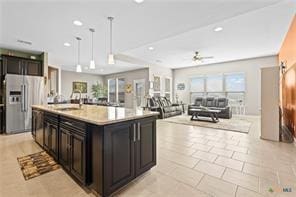 kitchen with stainless steel refrigerator with ice dispenser, sink, a center island with sink, pendant lighting, and a barn door