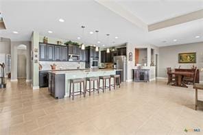 kitchen featuring pendant lighting, appliances with stainless steel finishes, a kitchen bar, and a center island with sink