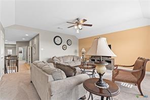 living room featuring ceiling fan, lofted ceiling, and light colored carpet