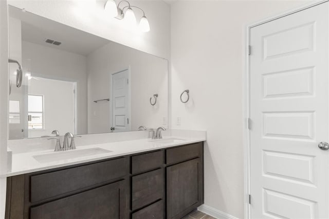 full bathroom featuring baseboards, visible vents, a sink, and double vanity