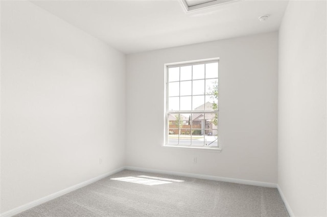 carpeted spare room with baseboards and attic access