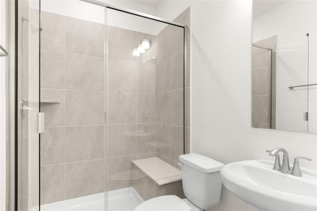 bathroom with a sink, toilet, and a shower stall
