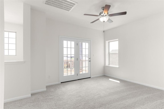 carpeted empty room with baseboards, ceiling fan, and visible vents