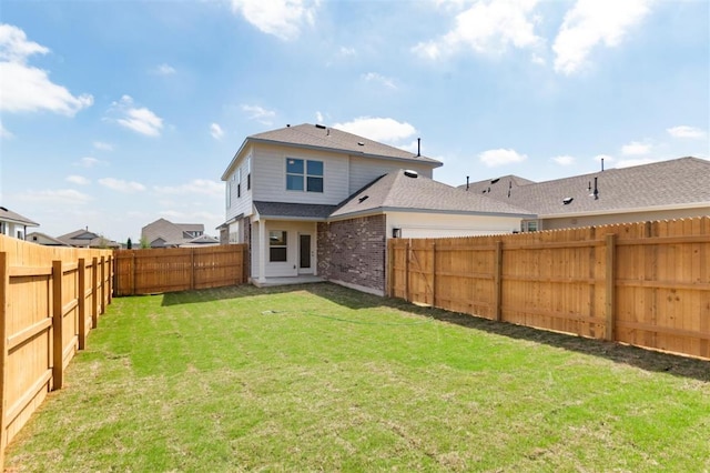 back of house with a fenced backyard, brick siding, and a lawn