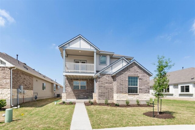 view of front of property with a balcony, brick siding, and a front yard
