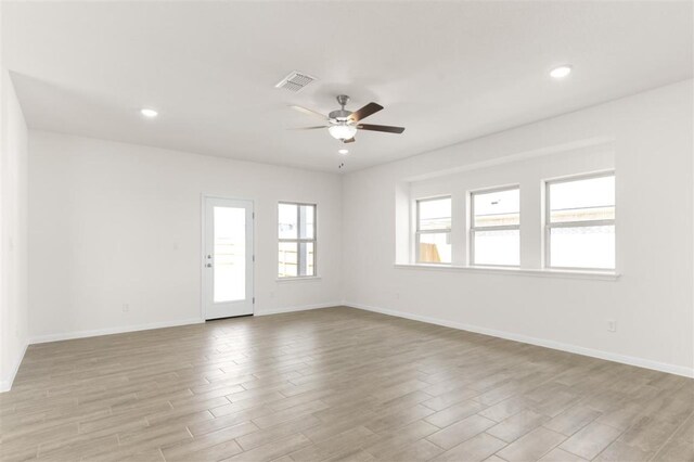 unfurnished room with light wood finished floors, baseboards, ceiling fan, and visible vents