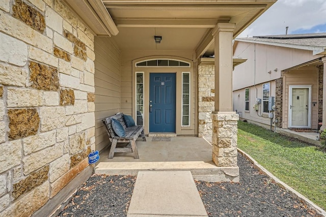 doorway to property with stone siding and a porch