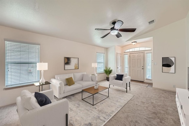 living area with light colored carpet, healthy amount of natural light, ceiling fan, and vaulted ceiling