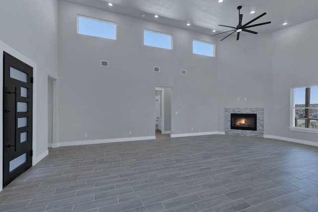 unfurnished living room featuring a towering ceiling and ceiling fan