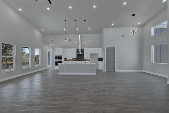 unfurnished living room with dark hardwood / wood-style flooring, sink, plenty of natural light, and a high ceiling