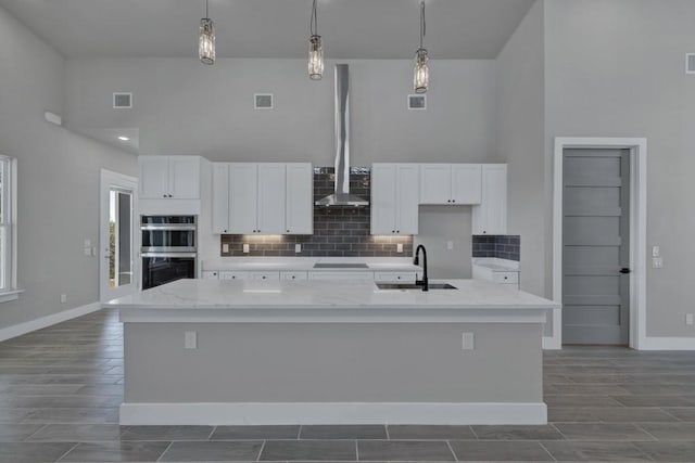 kitchen featuring hanging light fixtures, sink, a center island with sink, and stainless steel double oven