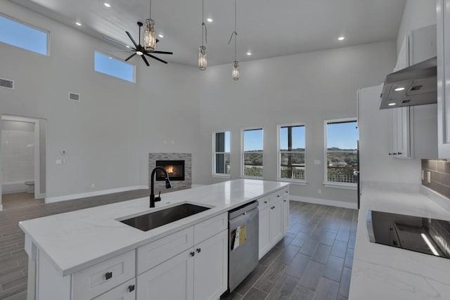 kitchen featuring sink, dishwasher, a center island, extractor fan, and light stone countertops