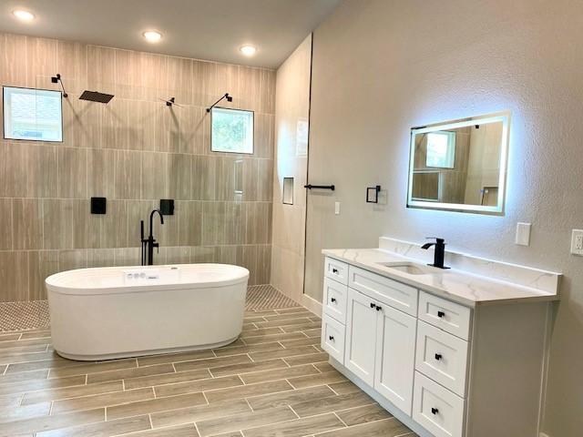 bathroom with vanity, tile walls, and separate shower and tub