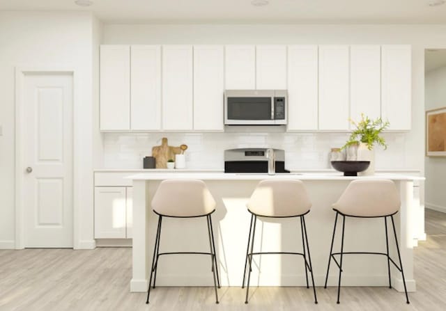 kitchen with decorative backsplash, an island with sink, stove, and white cabinets