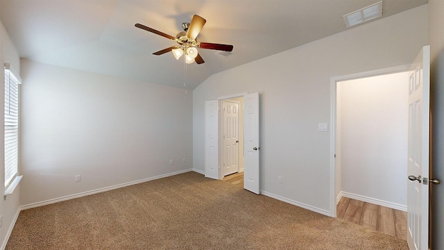 unfurnished bedroom with multiple windows, vaulted ceiling, light carpet, and ceiling fan