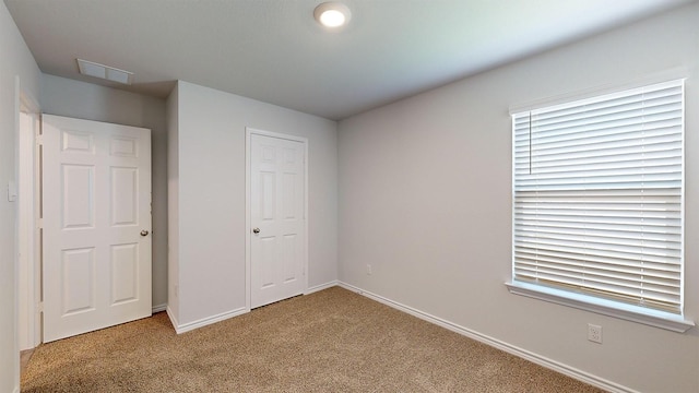 unfurnished bedroom with light colored carpet and a closet