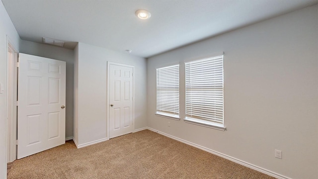 unfurnished bedroom featuring light colored carpet and a closet