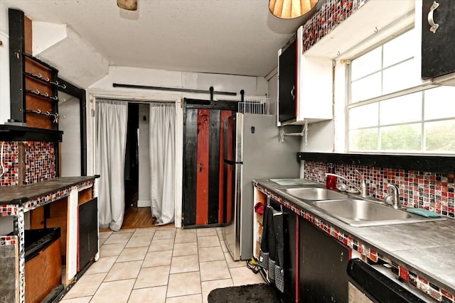 206 M L K Dr Unit B, Elgin, TX 78621 - kitchen featuring tasteful backsplash, light tile patterned floors, a sink, dishwashing machine, and freestanding refrigerator