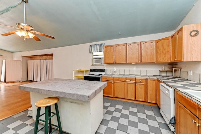 kitchen featuring a kitchen bar, a center island, ceiling fan, white dishwasher, and electric stove