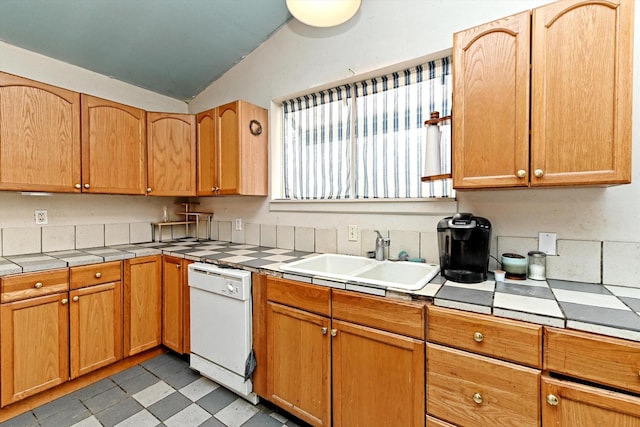 kitchen featuring lofted ceiling, tile countertops, dishwasher, and sink