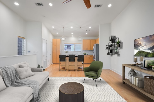 living area with light wood-style flooring, visible vents, and recessed lighting