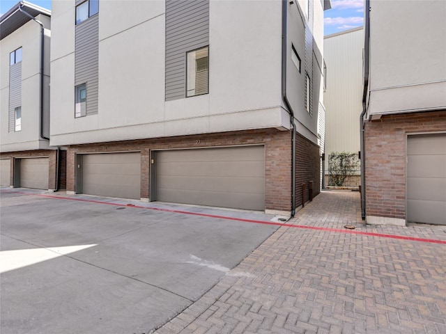 1702 S Lamar Blvd Unit 22, Austin, TX 78704 - view of property exterior featuring brick siding, a garage, stucco siding, and driveway