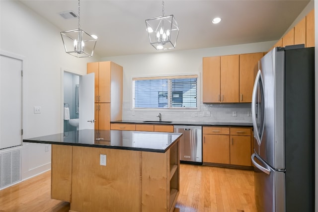1702 S Lamar Blvd Unit 22, Austin, TX 78704 - kitchen featuring appliances with stainless steel finishes, decorative backsplash, light wood-type flooring, a chandelier, and a center island