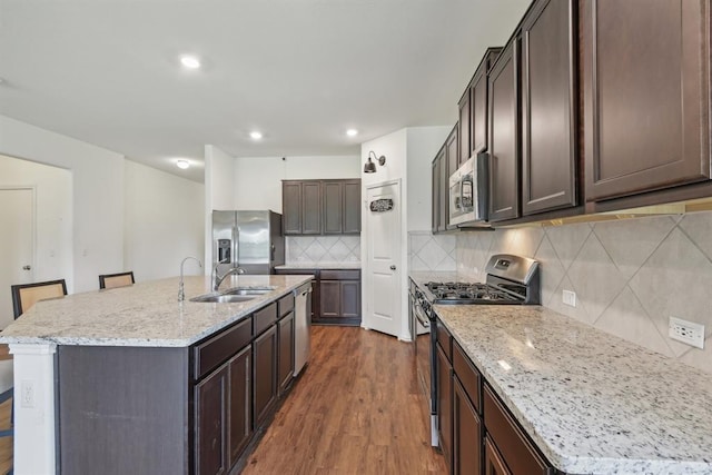 kitchen featuring sink, appliances with stainless steel finishes, a kitchen island with sink, dark hardwood / wood-style floors, and decorative backsplash