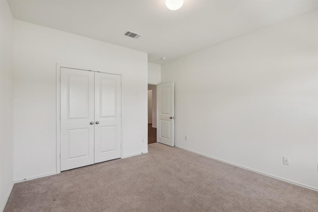 unfurnished bedroom featuring light carpet and a closet