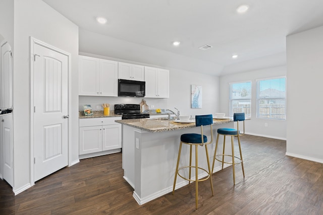 kitchen featuring a kitchen island with sink, white cabinetry, dark hardwood / wood-style floors, light stone counters, and black appliances