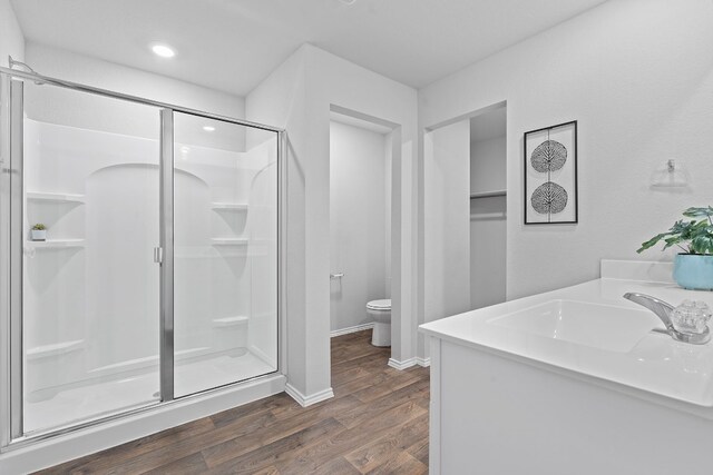 bathroom featuring vanity, hardwood / wood-style floors, a shower with shower door, and toilet