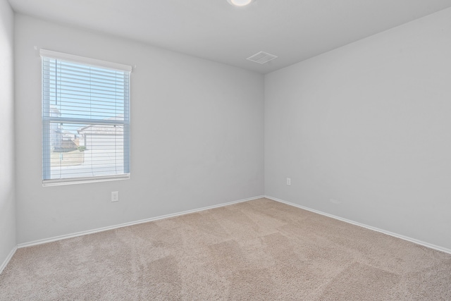 carpeted spare room with visible vents and baseboards