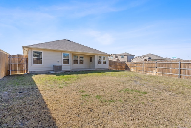 back of house with a fenced backyard, a lawn, and central air condition unit