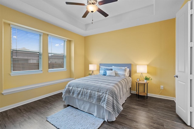 bedroom featuring dark hardwood / wood-style floors, ceiling fan, and a tray ceiling