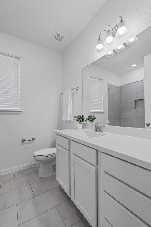 bathroom with vanity, tiled shower, tile patterned floors, and toilet