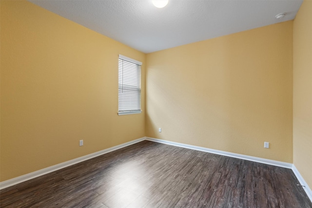 empty room with a textured ceiling and dark hardwood / wood-style flooring