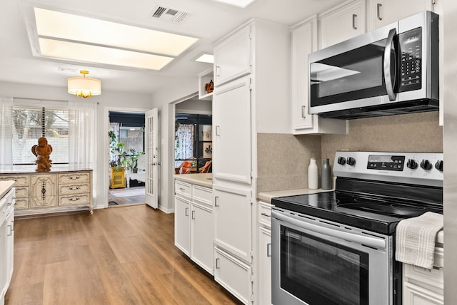 kitchen featuring white cabinetry, decorative backsplash, stainless steel appliances, and light wood-type flooring