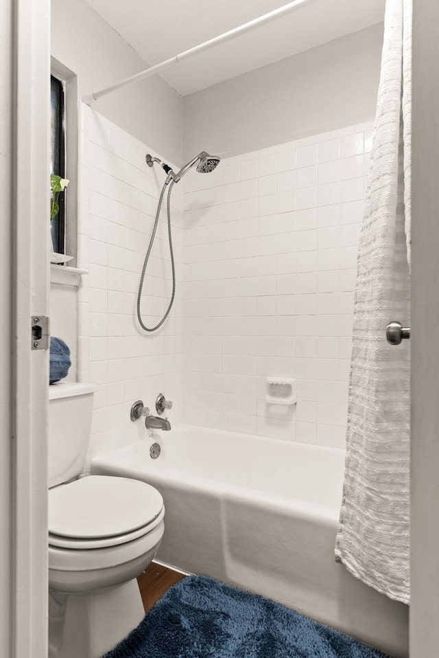 bathroom featuring shower / bathtub combination with curtain, hardwood / wood-style floors, and toilet