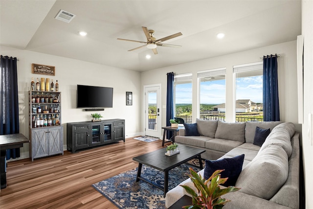 living room with bar, wood-type flooring, and ceiling fan