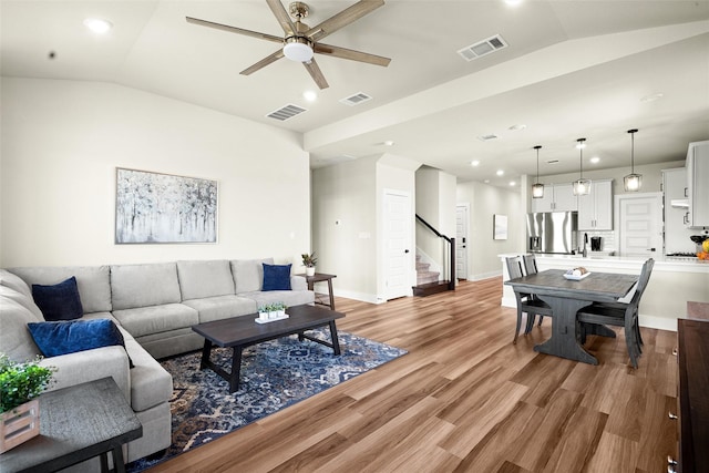 living room with ceiling fan, lofted ceiling, and hardwood / wood-style floors