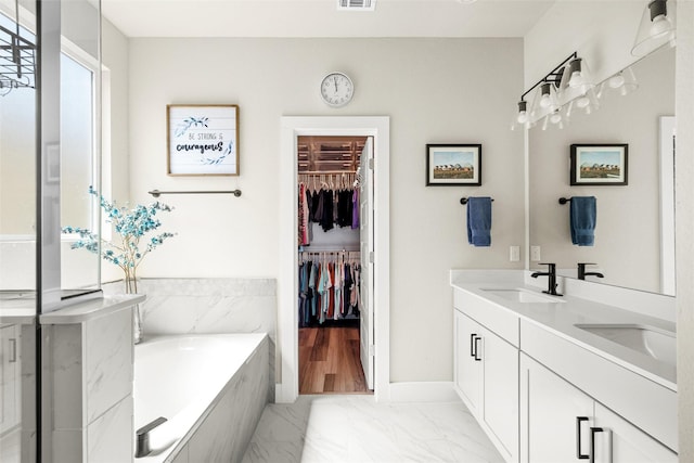 bathroom featuring vanity and tiled bath