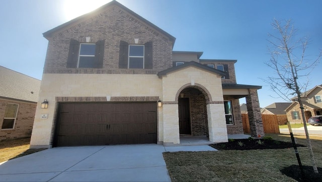 view of front of property with brick siding, stone siding, an attached garage, and concrete driveway